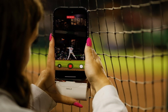 Evelyn filming baseball content from behind the net